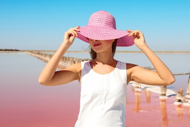 Photo of Beautiful woman with hat posing near pink lake on summer day