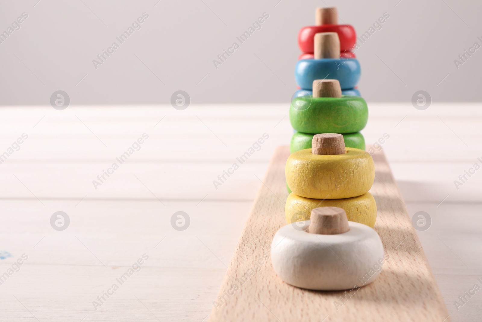 Photo of Motor skills development. Stacking and counting game pieces on white table, closeup. Space for text