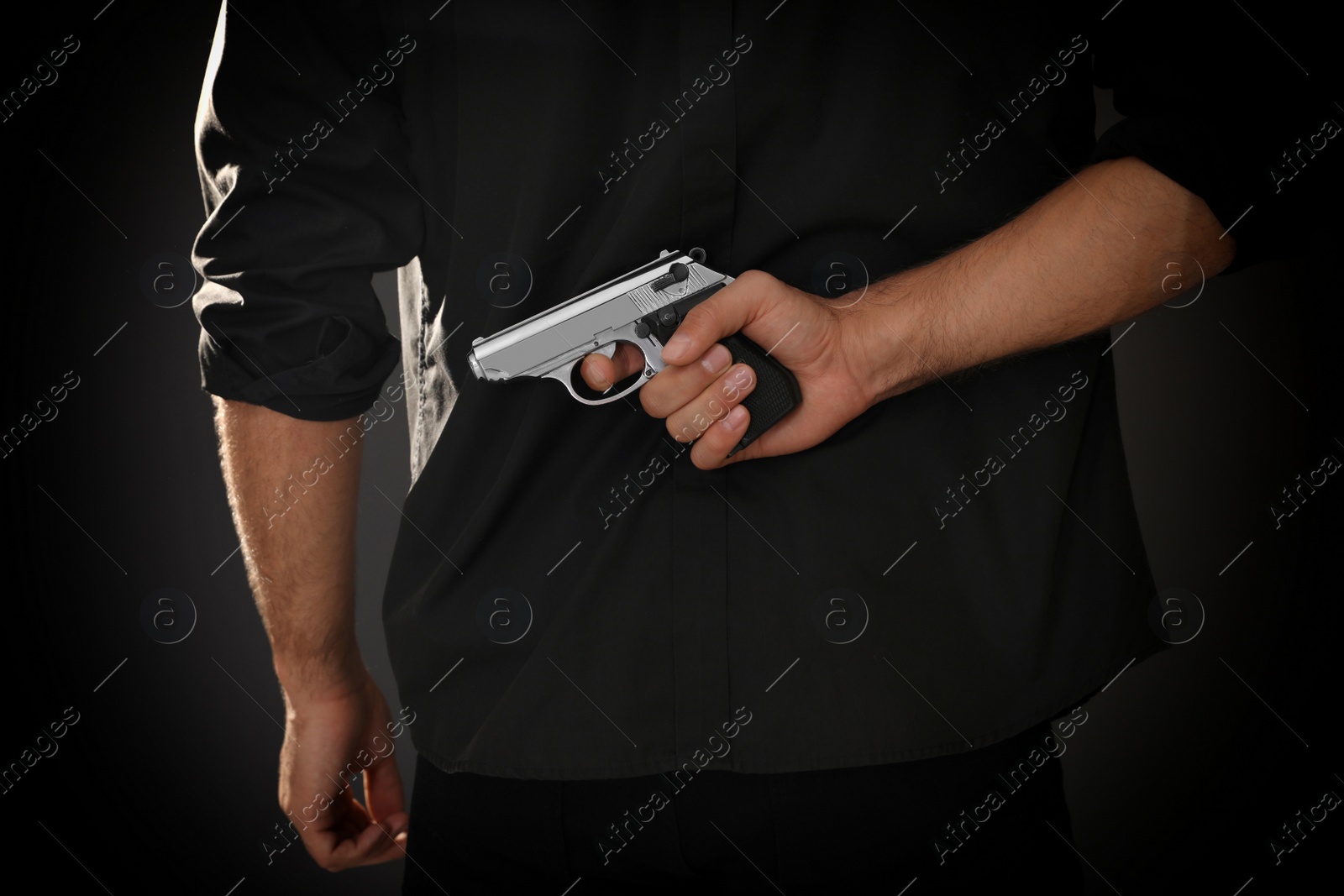 Photo of Professional killer with gun on black background, closeup