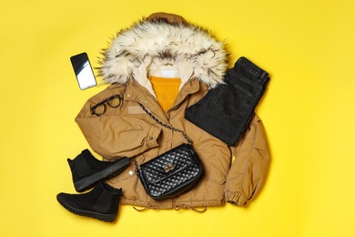 Flat lay composition with winter clothes and boots on yellow background