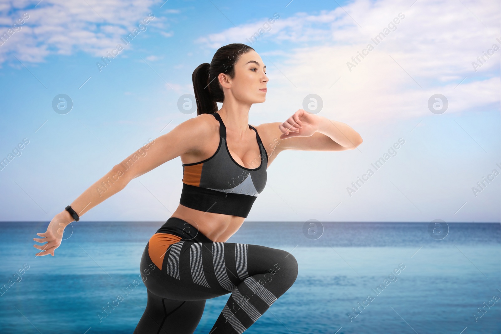 Image of Athletic young woman running near sea on sunny day