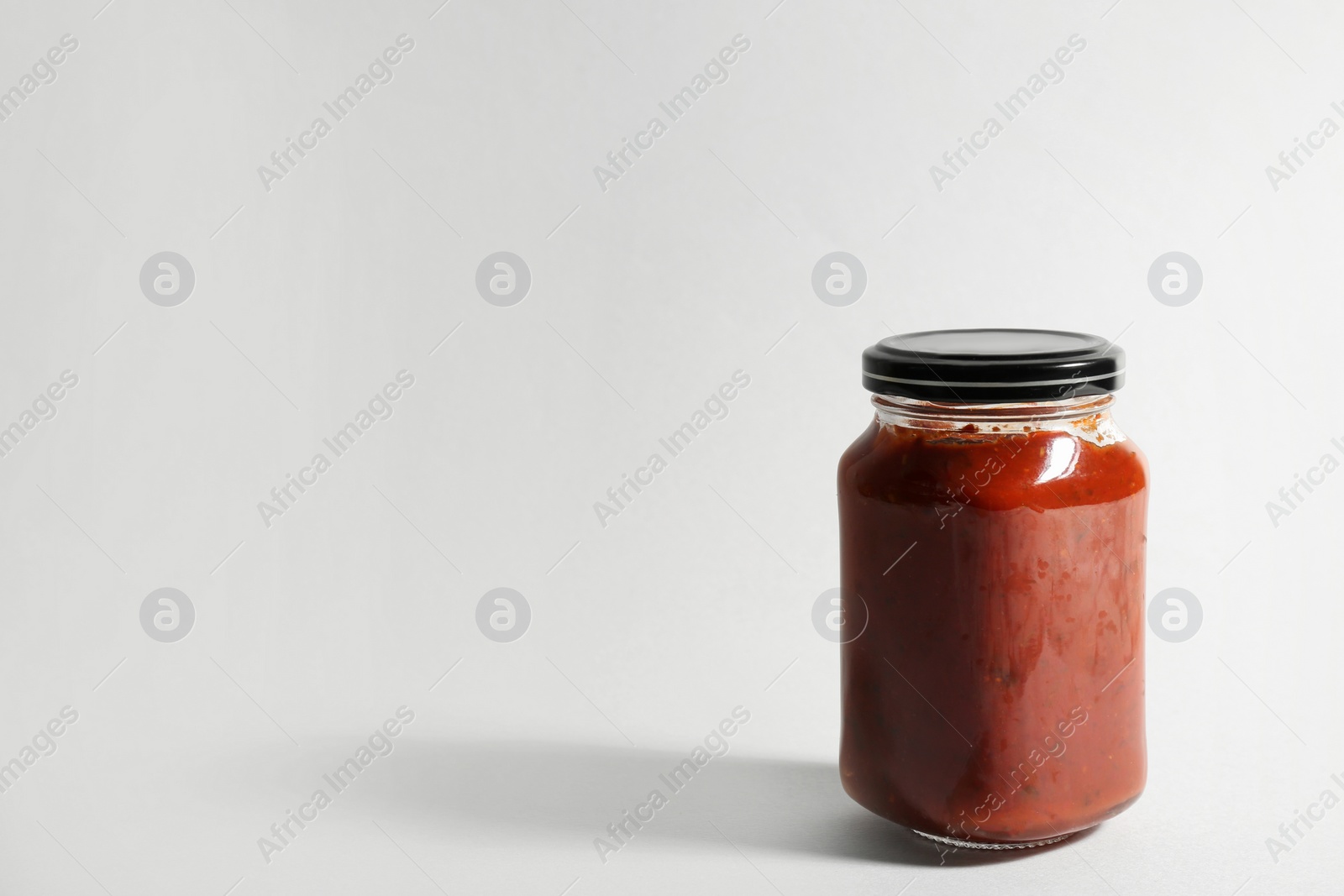 Photo of Jar of tomato paste on white background. Space for text