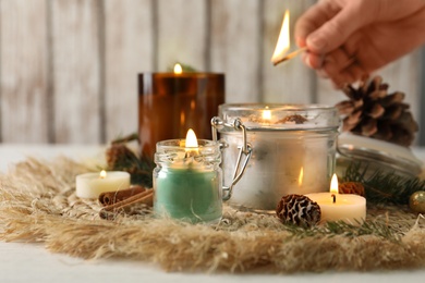 Photo of Woman lighting conifer candles on table, closeup