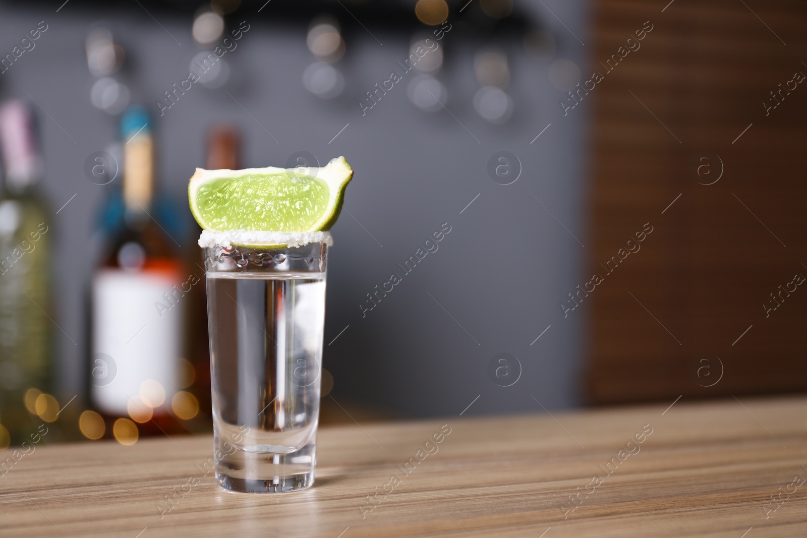 Photo of Mexican Tequila with salt and lime slice on bar counter. Space for text