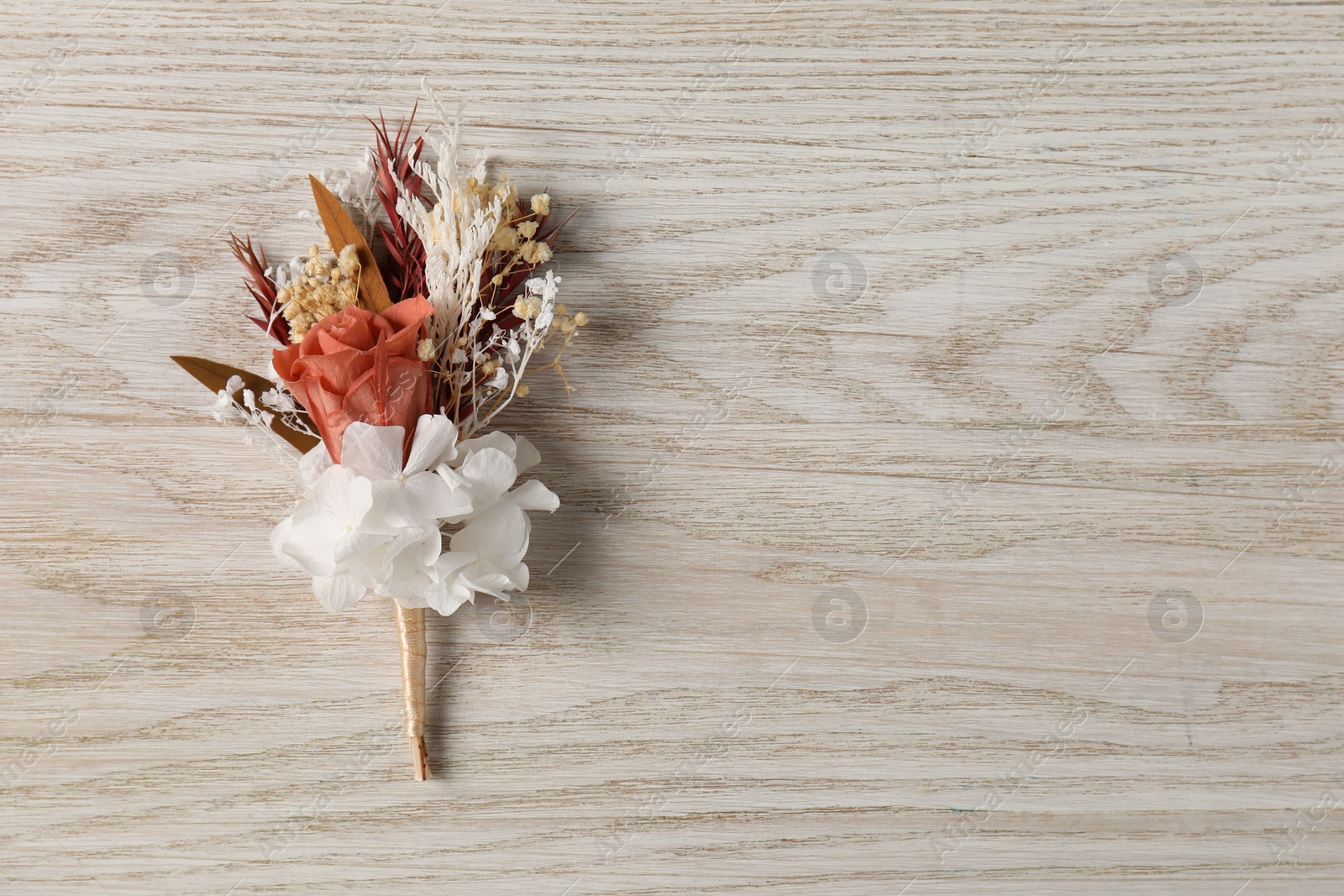 Photo of Stylish boutonniere on white wooden table, top view. Space for text