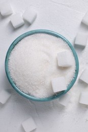 Different types of sugar in bowl on white table, flat lay