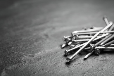 Photo of Many metal nails on grey background. Space for text