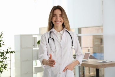 Happy female doctor offering handshake in clinic