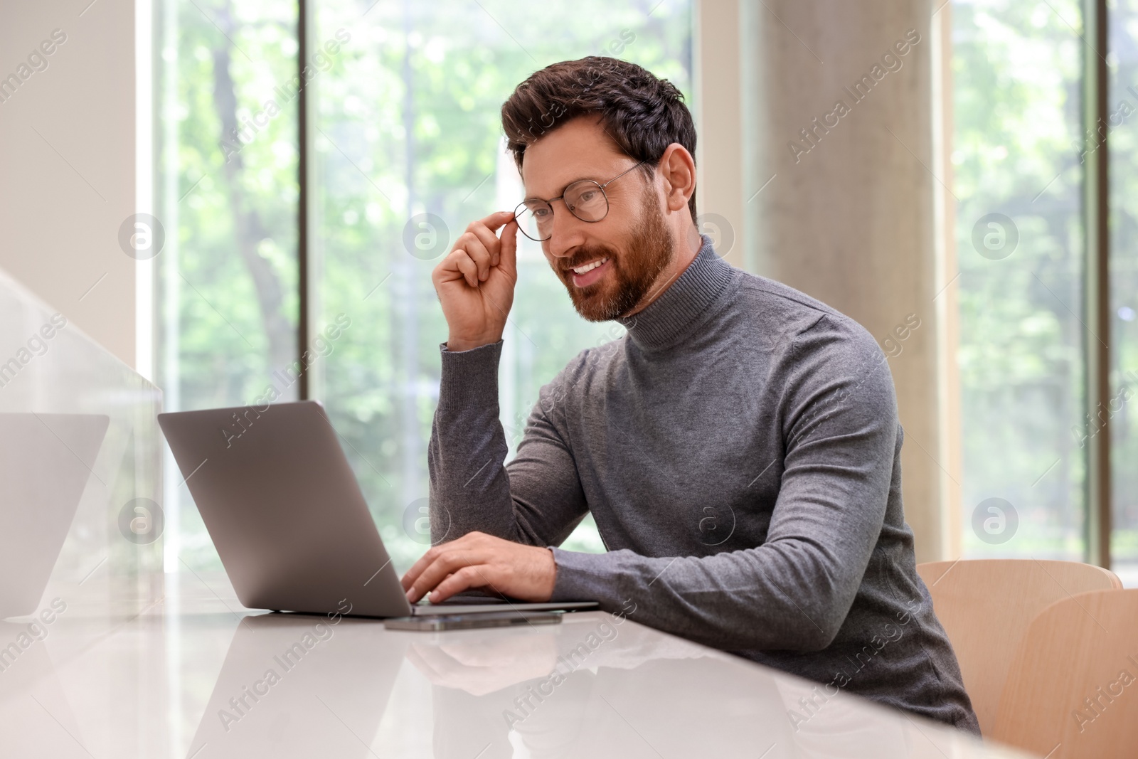 Photo of Man working on laptop at table in cafe