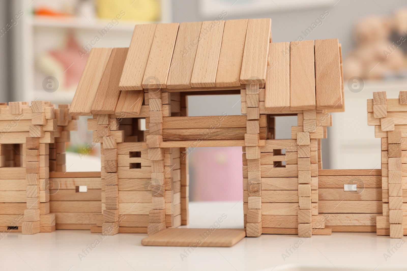 Photo of Wooden entry gate on white table indoors. Children's toy