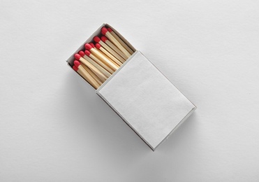 Photo of Cardboard box with matches on white background, top view. Space for design