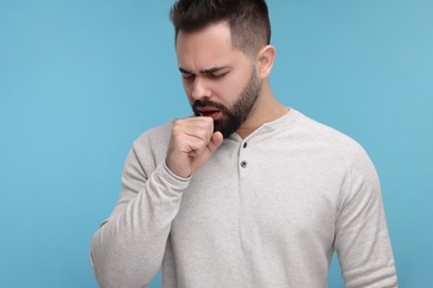 Photo of Sick man coughing on light blue background