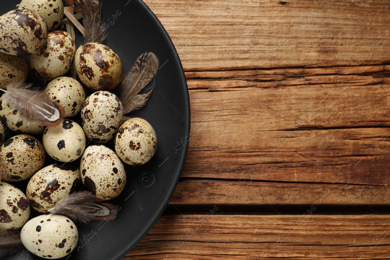Photo of Plate with quail eggs on wooden table, top view. Space for text