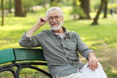 Portrait of happy grandpa with glasses on bench in park