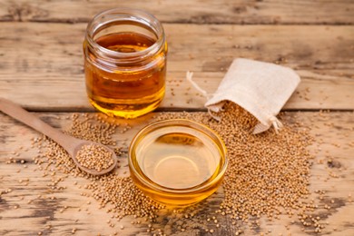 Photo of Natural oil and mustard seeds on wooden table