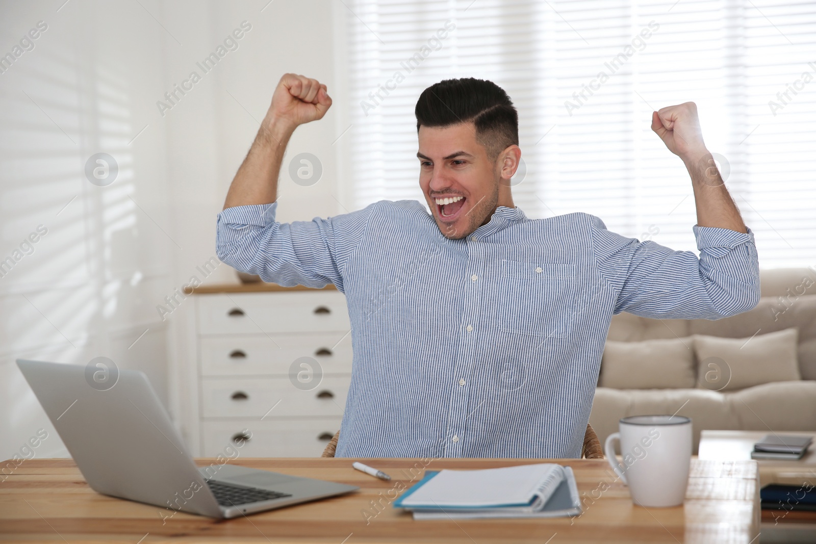 Photo of Emotional man participating in online auction using laptop at home