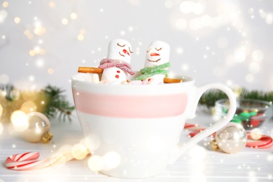 Image of Marshmallow snowmen in cup with hot drink on white wooden table. Bokeh effect 