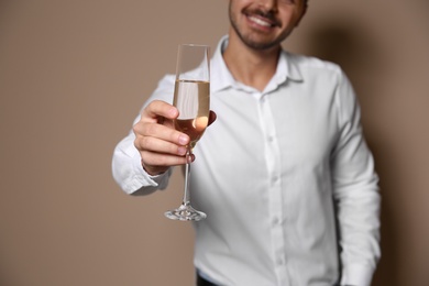 Handsome man with glass of champagne on color background, closeup