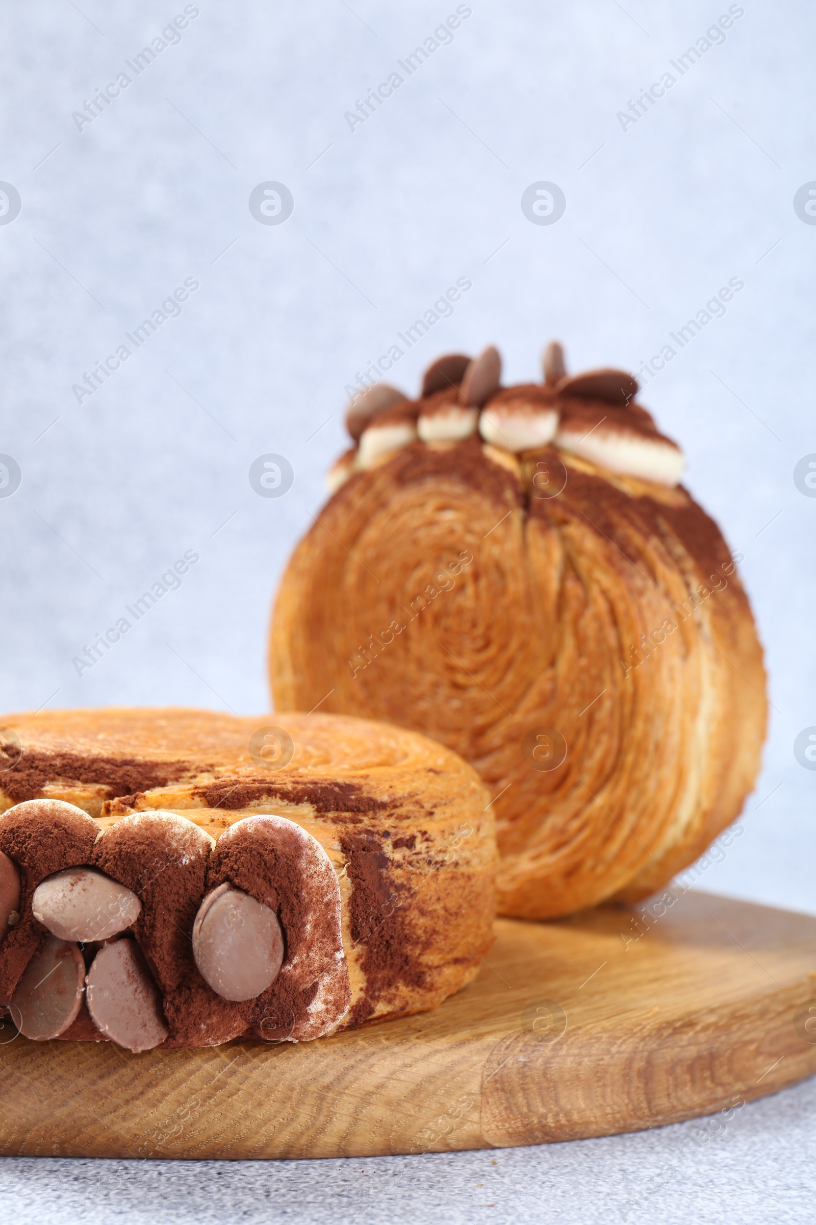 Photo of Supreme croissants with chocolate chips and cream on grey table, closeup. Tasty puff pastry