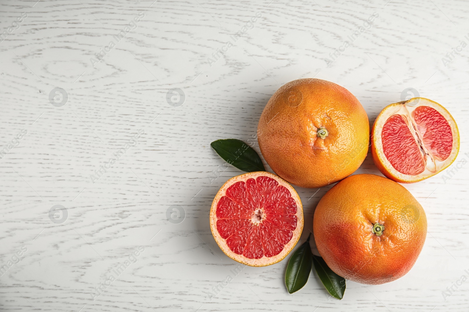 Photo of Fresh tasty grapefruits on white wooden background, top view with space for text