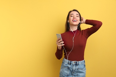 Photo of Young woman using phone for listening to music on color background