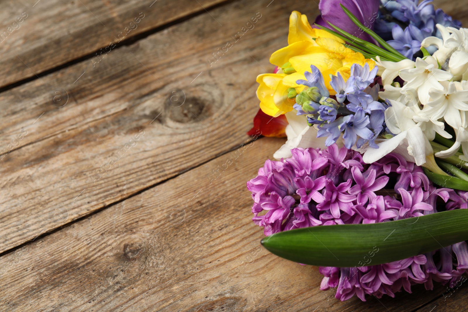 Photo of Bouquet of beautiful spring flowers on wooden table, closeup. Space for text