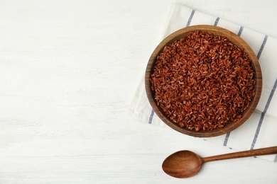 Photo of Flat lay composition with delicious cooked brown rice on white wooden table. Space for text