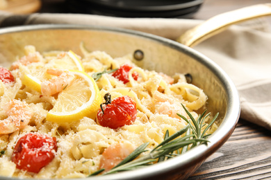 Delicious pasta with shrimps on wooden table, closeup