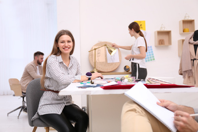 Photo of Fashion designer with colleagues creating new clothes in studio