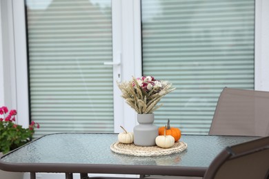 Photo of Beautiful bouquet of dry flowers and small pumpkins on glass table outdoors