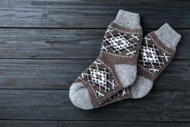 Photo of Warm knitted socks on black wooden background, flat lay. Space for text