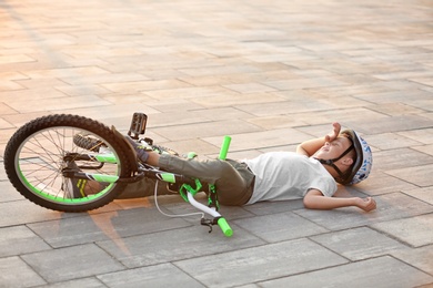 Photo of Little boy fallen off his bicycle on street