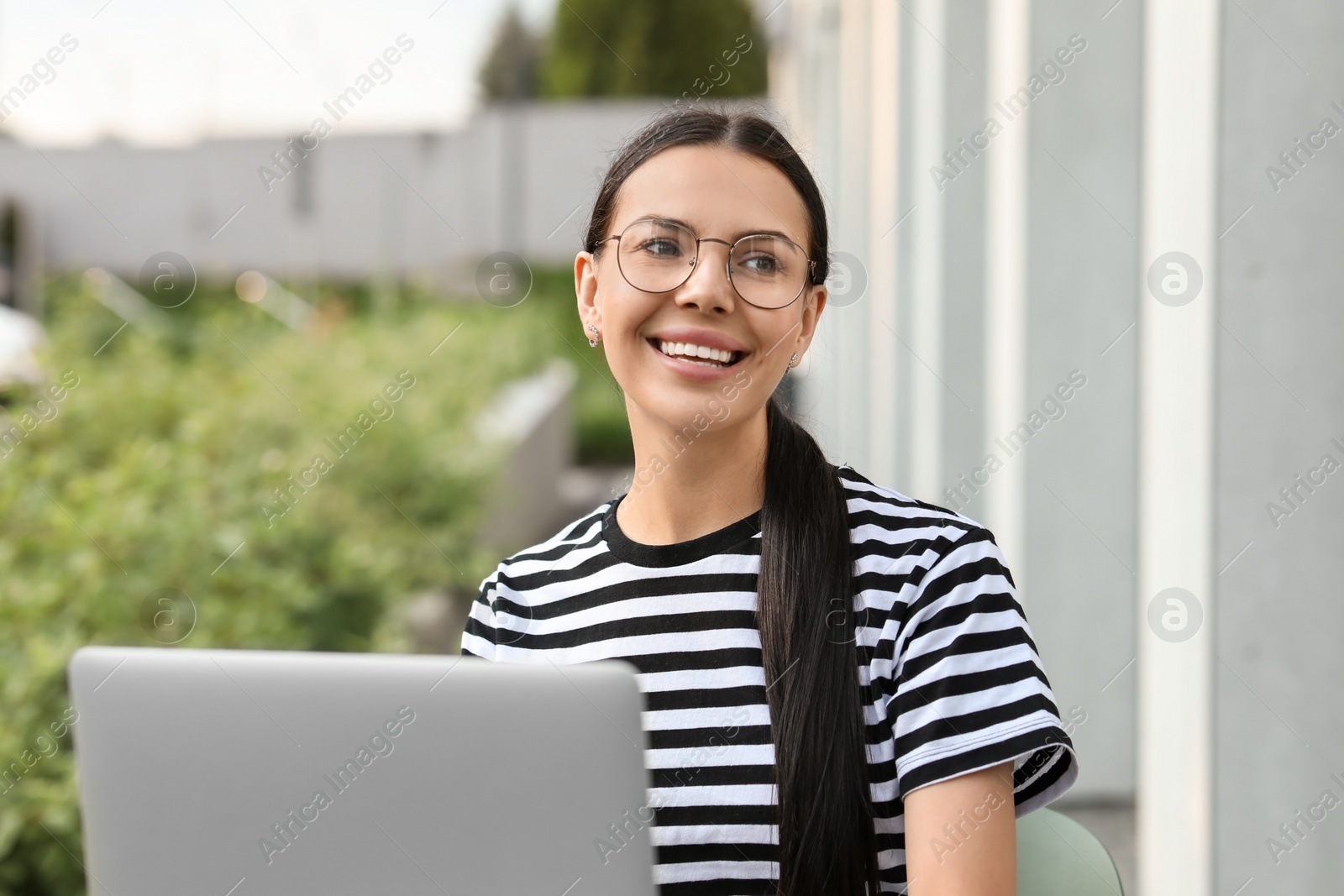 Photo of Happy young woman using modern laptop outdoors