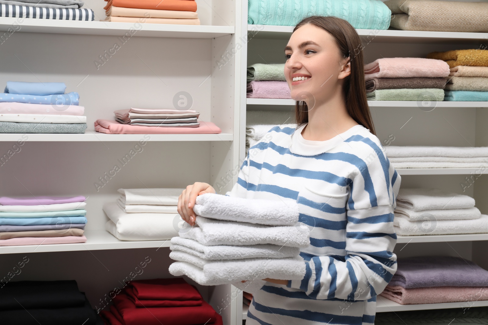 Photo of Happy customer holding stack of towels in linen shop, space for text