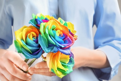 Photo of Woman holding rainbow rose flowers, closeup