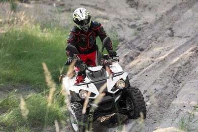 Photo of Man driving modern quad bike on sandy road. Extreme sport