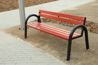 Empty red wooden bench in city park