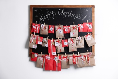 Photo of Blackboard with Christmas advent calendar on white wall indoors