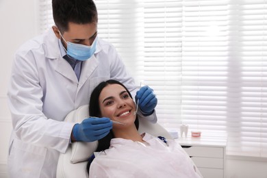 Dentist examining young woman's teeth in modern clinic