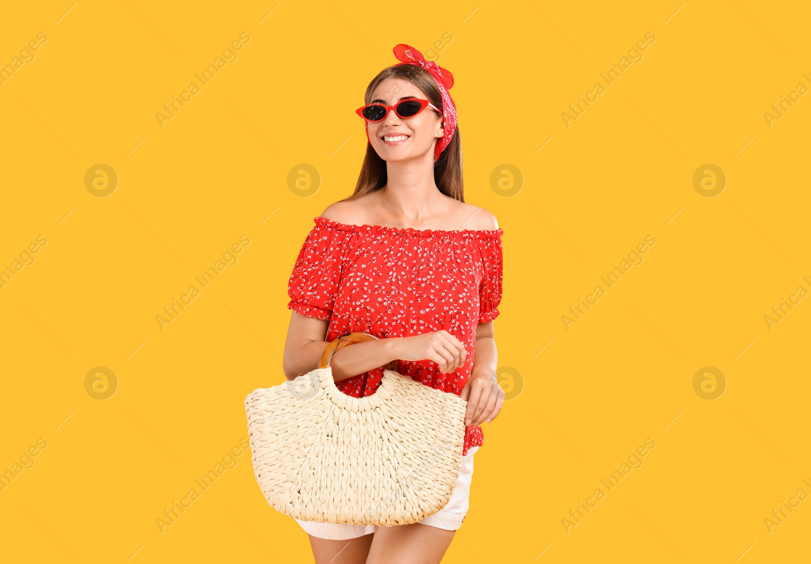 Photo of Beautiful young woman with stylish straw bag on yellow background