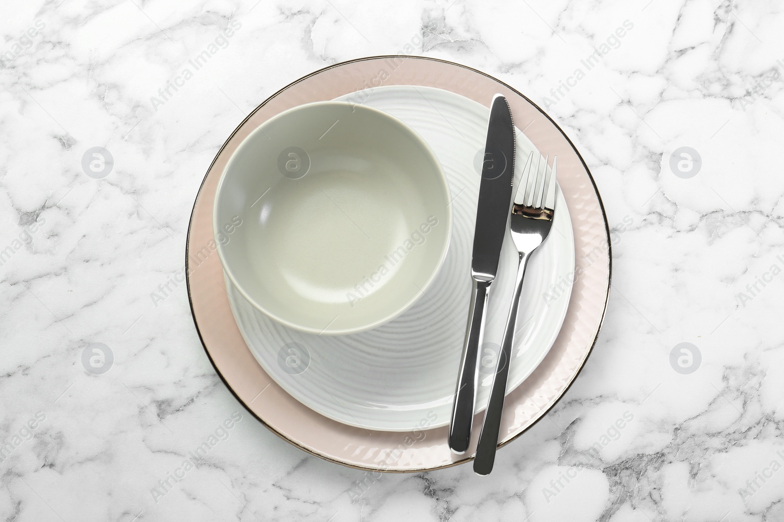 Photo of Clean plates, bowl and cutlery on white marble table, top view