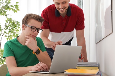 Father helping his teenager son with homework indoors