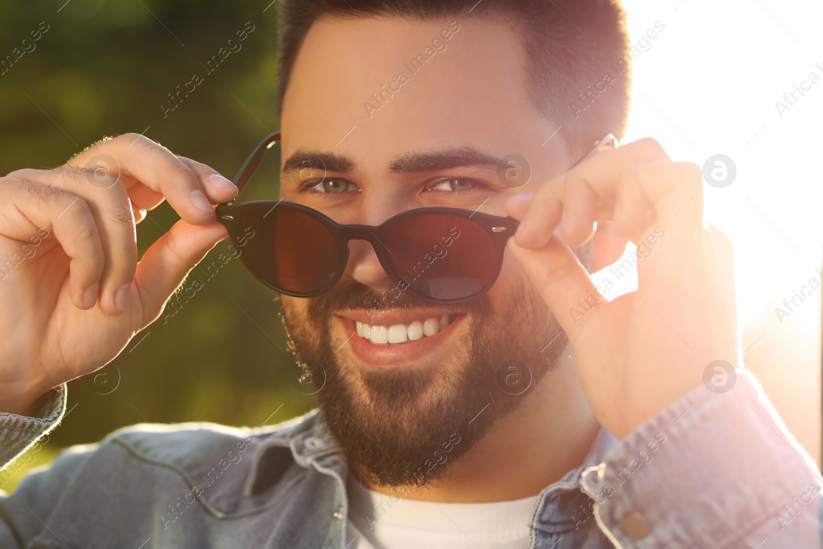 Photo of Handsome smiling man in sunglasses outdoors on sunny day