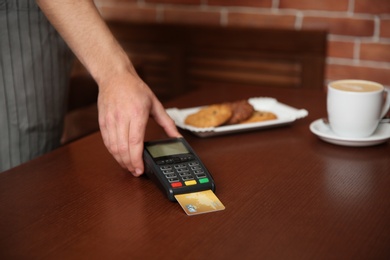 Waiter with terminal for contactless payment in cafe, closeup