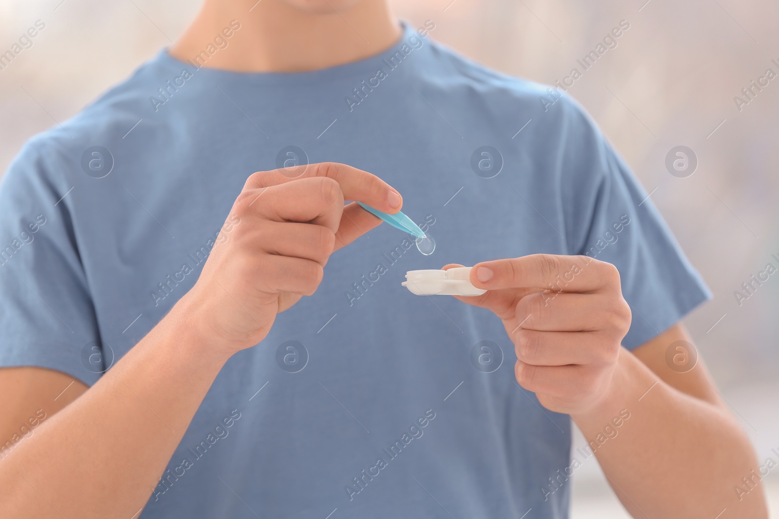 Photo of Teenage boy taking contact lens from container, closeup of hands