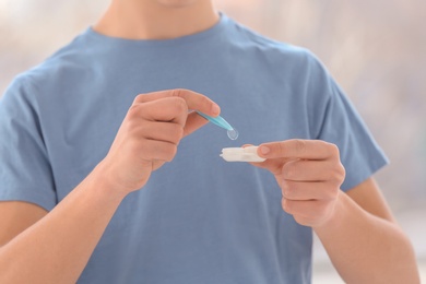 Teenage boy taking contact lens from container, closeup of hands