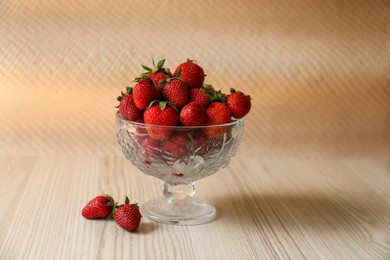 Photo of Glass dessert bowl with ripe strawberries on white wooden table