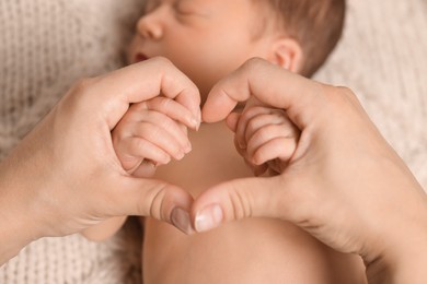 Photo of Mother with her newborn baby, closeup. Woman making heart shape with hands. Lovely family