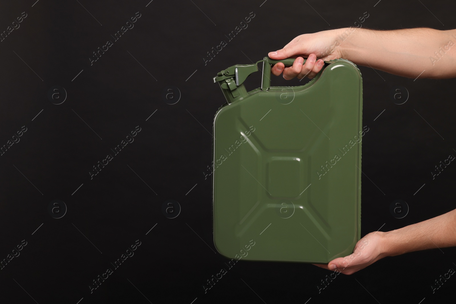 Photo of Man holding khaki metal canister on black background, closeup. Space for text