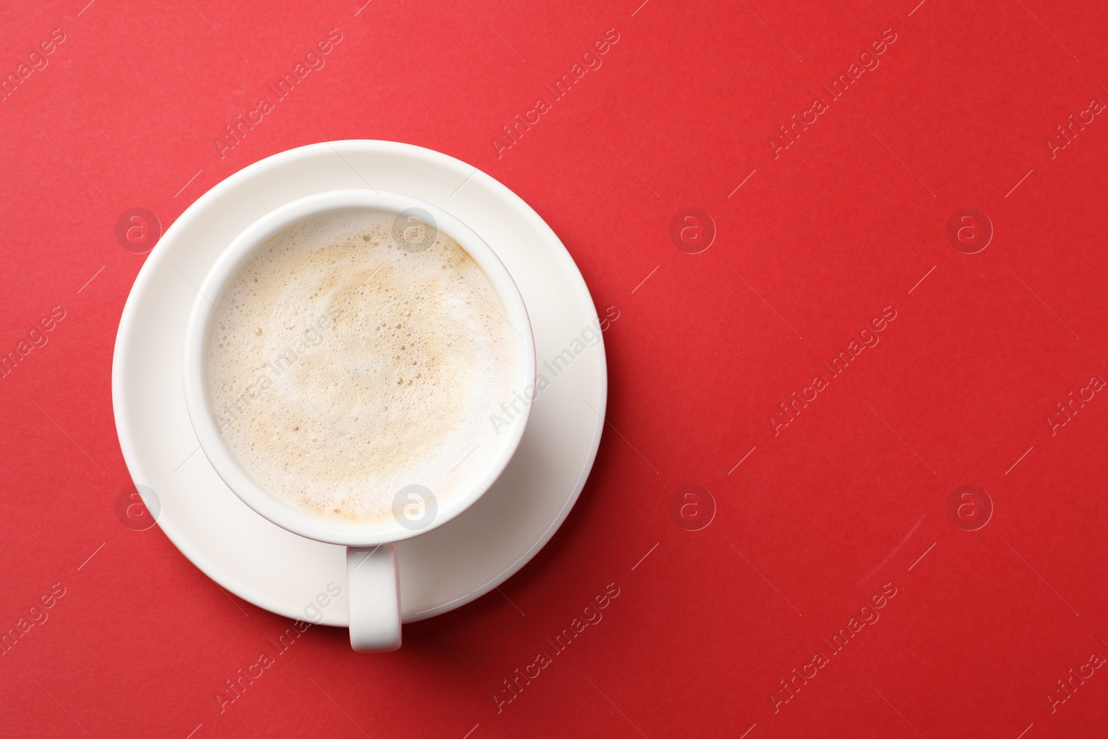 Photo of Cup of aromatic coffee on red background, top view. Space for text